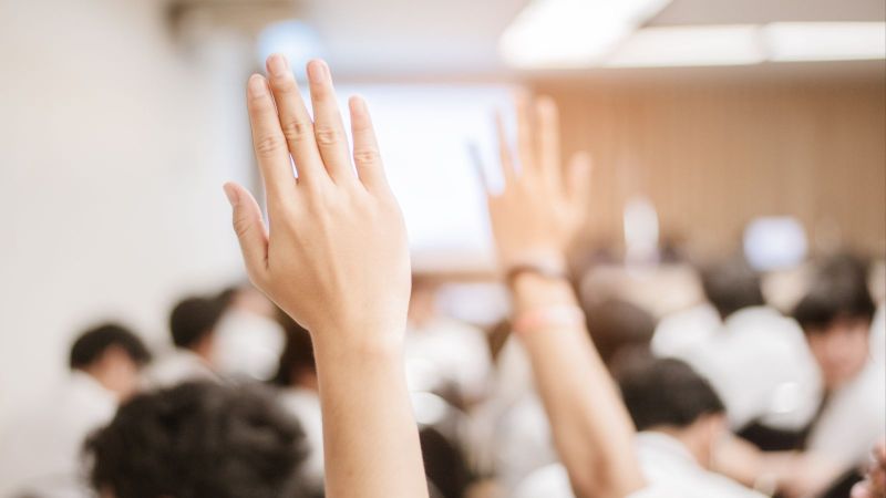 Bürgerbeteiligung - erhobene Hand im vollen Sitzungssaal