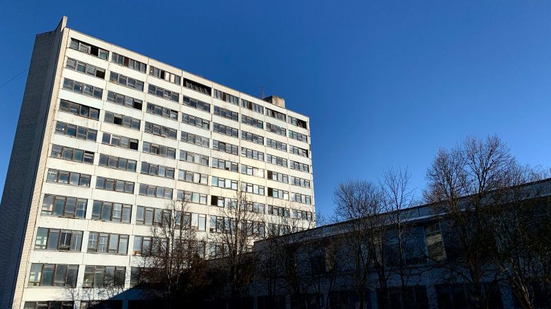 Verlassenes Hochhaus eines ehemaligen Fabrikgeländes mit zahlreichen Fenstern und sichtbaren Alterungsspuren. Das Gebäude ragt vor bewölktem Himmel auf und vermittelt den Eindruck industriellen Verfalls.