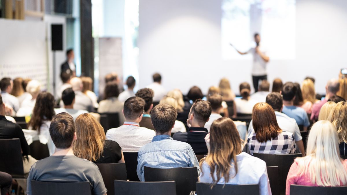 Bild eines Konferenzvortrages mit Blick auf den Sprecher auf dem Podium.